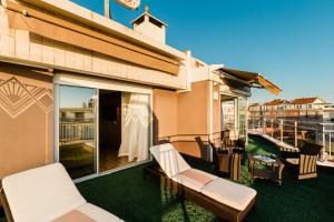 a patio with white chairs and a balcony at Hôtel Hélios in Juan-les-Pins