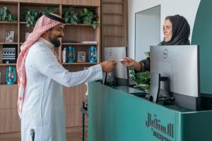a woman giving a man a card at a cash register at Shada Hotel Shatea - فندق شدا الشاطئ in Jeddah