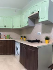 a kitchen with green cabinets and a washing machine at Улица Склизкова д116 к.6 in Tver