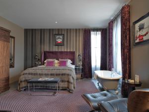 a bedroom with a bed and a tub in a room at Malmaison Dundee in Dundee
