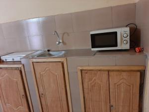 a small kitchen with a microwave and a sink at Appartement chambre salon climatisées, cuisine in Bamako