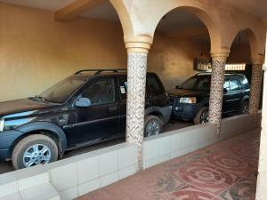 dois carros estacionados num parque de estacionamento com colunas em Appartement chambre salon climatisées, cuisine em Bamako