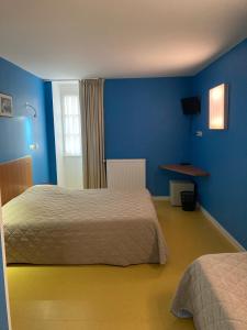 a bedroom with two beds and a blue wall at L'ETAPE DE SANTENAY in Santenay