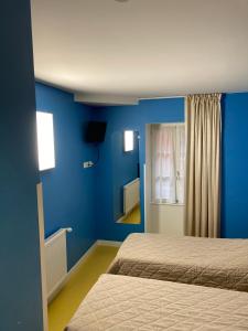 a room with two beds and a blue wall at L'ETAPE DE SANTENAY in Santenay