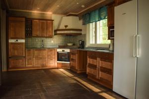 eine Küche mit Holzschränken und einem Kühlschrank in der Unterkunft Loma-Autio Tähti Villa in Puumala