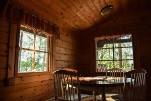 a dining room with a table and two windows at Loma-Autio Tähti Villa in Puumala