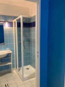 ein blaues Bad mit einer Dusche und einem Waschbecken in der Unterkunft L'ETAPE DE SANTENAY in Santenay