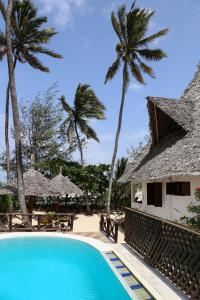 un complejo con piscina y palmeras en Kipepeo Lodge Zanzibar, en Jambiani