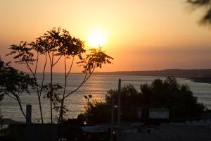 a sunset over a body of water with the sun setting at Sole A Sunset Bay - San Gregorio in Patù