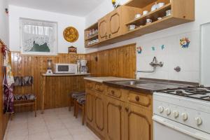 a kitchen with wooden cabinets and a white stove top oven at Familia Nyaraló 117 in Balatonmáriafürdő