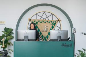 a woman sitting at a desk with two computers at Shada Hotel Shatea in Jeddah