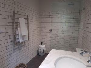 a white tiled bathroom with a sink and towels at Mt Lofty Botanic Garden Studio in Crafers