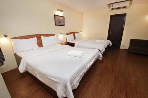 2 Betten in einem Hotelzimmer mit weißer Bettwäsche in der Unterkunft Westend Hotel in Matheran