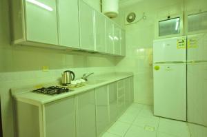 a white kitchen with a stove and a refrigerator at ريتان للشقق المخدومة - Retan Serviced Apartments in Taif
