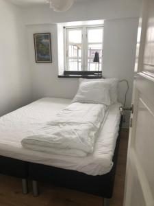 Una cama con sábanas blancas y una ventana en una habitación en Bækgaardens bed and breakfast en Odense
