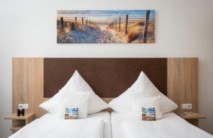 2 Betten mit weißen Kissen in einem Hotelzimmer in der Unterkunft Nordsee Hotel Borkum in Borkum