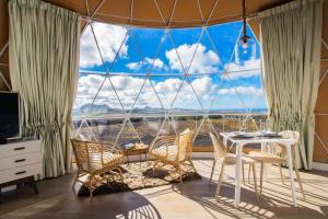 Habitación con mesa, sillas y ventana grande. en Eslanzarote Luxurious Eco Dome Experience, en Teguise