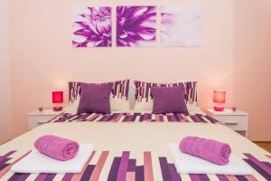 een slaapkamer met een groot bed met paarse kussens bij Apartments Zenta Split in Split