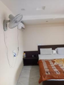 Vamoose Akshat Chindwara في Chhindwāra: غرفة نوم مع سرير مع مروحة على الحائط