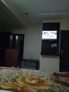 Vamoose Akshat Chindwara في Chhindwāra: غرفة نوم مع سرير وتلفزيون على الحائط