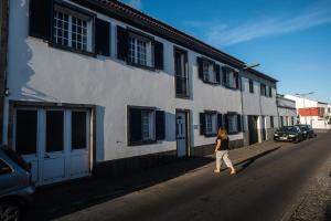 Una donna che cammina per una strada accanto a un edificio di Casa dos Guerra a Ponta Delgada