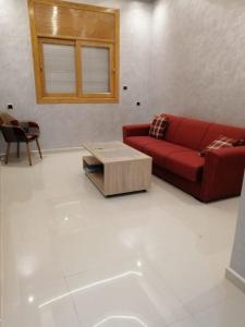 a living room with a red couch and a coffee table at Joli appartement Casablanca ain sebaa in Casablanca