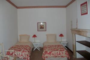 2 Betten in einem Zimmer mit weißen Wänden und einem Kamin in der Unterkunft La Cochetière in Cheviré-le-Rouge