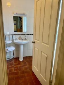 a white bathroom with a sink and a mirror at An Stór Townhouse in Midleton