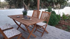 drewniany stół i 2 krzesła na patio w obiekcie Room near the Airport w mieście Pikérmion