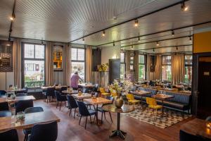 a dining room with tables and chairs and windows at Hotel Breeburg in Bergen