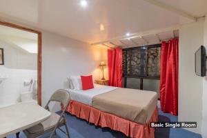 a bedroom with a bed and a window with red curtains at South Drive Baguio Manor in Baguio