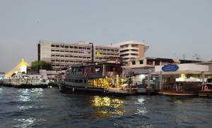 een groep boten aangemeerd in een rivier met gebouwen bij Sabai Sabai Liveaboard Bangkok in Bangkok