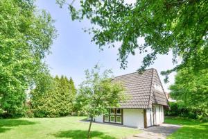 una pequeña casa blanca en un patio con árboles en Landhaus Braband Ferienhaus ohne WLAN - Christian-Brütt-Weg, en Cuxhaven