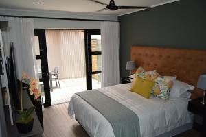 um quarto com uma cama com almofadas amarelas e uma varanda em The Guesthouse 6 on Vrede em Joanesburgo