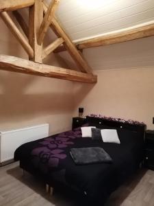 um quarto com uma grande cama preta num quarto com tectos em madeira em Cocottes & Colibri em Châtellerault