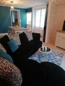 ein Wohnzimmer mit einem schwarzen Sofa und einem Tisch in der Unterkunft Cocottes & Colibri in Châtellerault