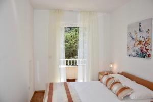 a white bedroom with a bed and a window at Pervanovo Apartments with Free Parking in Dubrovnik