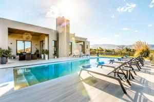una piscina con sillas y una casa en Villa Vega, en La Canea