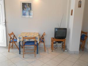 a dining room with a table and chairs and a tv at Apartments Špadina in Tisno