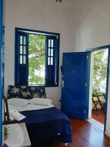 a bedroom with a blue bed and two windows at Brasileranza Hostel in Niterói