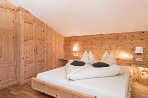 Wasserfall Moarlhof Kastelruth في كاستيلِروتّو: غرفة نوم بسرير ابيض بجدران خشبية