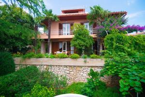 a house on a stone wall with trees and plants at Apartments Ljerka in Rabac