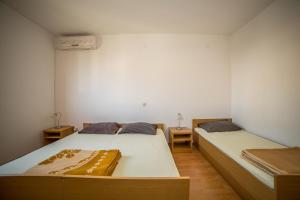 two beds in a small room with two tables at Apartments Grulović in Srima