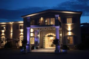 a large house with a balcony at night at Riviera Resort Airport Modlin in Olszewnica Nowa