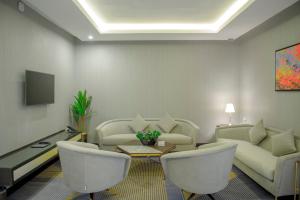 sala de estar con muebles blancos, mesa y sillas en Gorash Hotel, en Khamis Mushayt