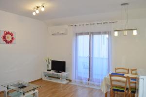 a living room with a television and a table with chairs at Apartments Vilim Tisno in Tisno