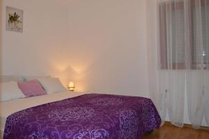a purple bed in a white room with a window at Apartments Vilim Tisno in Tisno