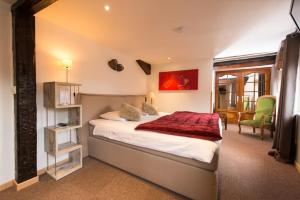 ein Schlafzimmer mit einem Bett mit einer roten Decke darauf in der Unterkunft Hotel SPA Restaurant Au Cheval Blanc in Ribeauvillé