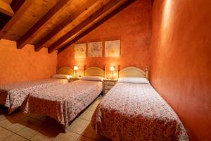2 Betten in einem Zimmer mit roten Wänden in der Unterkunft El Mirador del Alberche III in Navaluenga