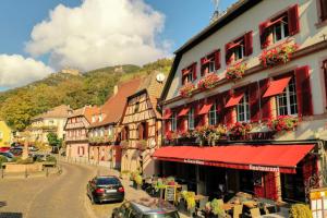 a street in a town with buildings and cars at Hotel SPA Restaurant Au Cheval Blanc in Ribeauvillé